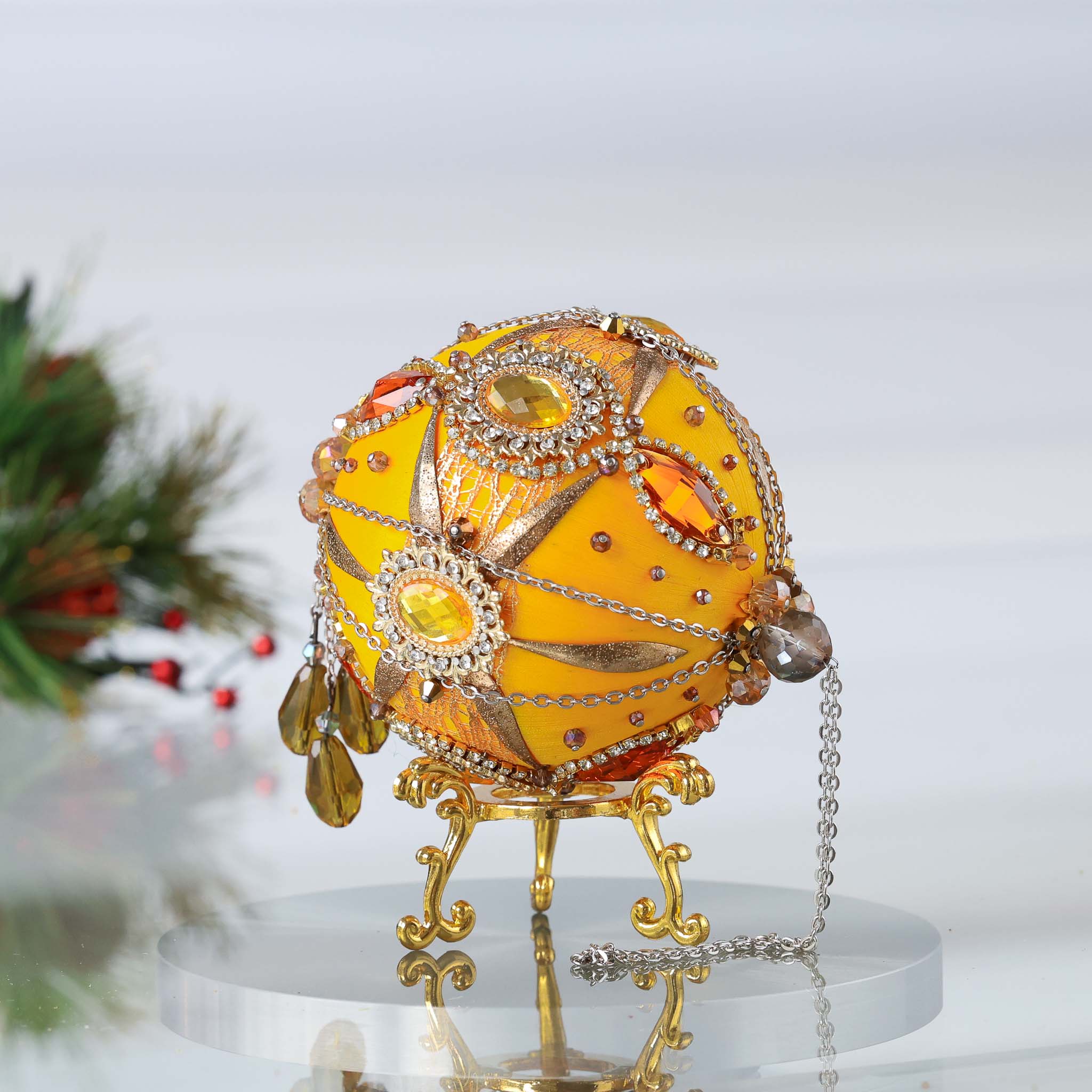 A side view of a handmade yellow satin  push pin ornament with gemstones featuring bead tassel and gold chains with holiday branch in the background by Whim5seasons. (Light Yellow)