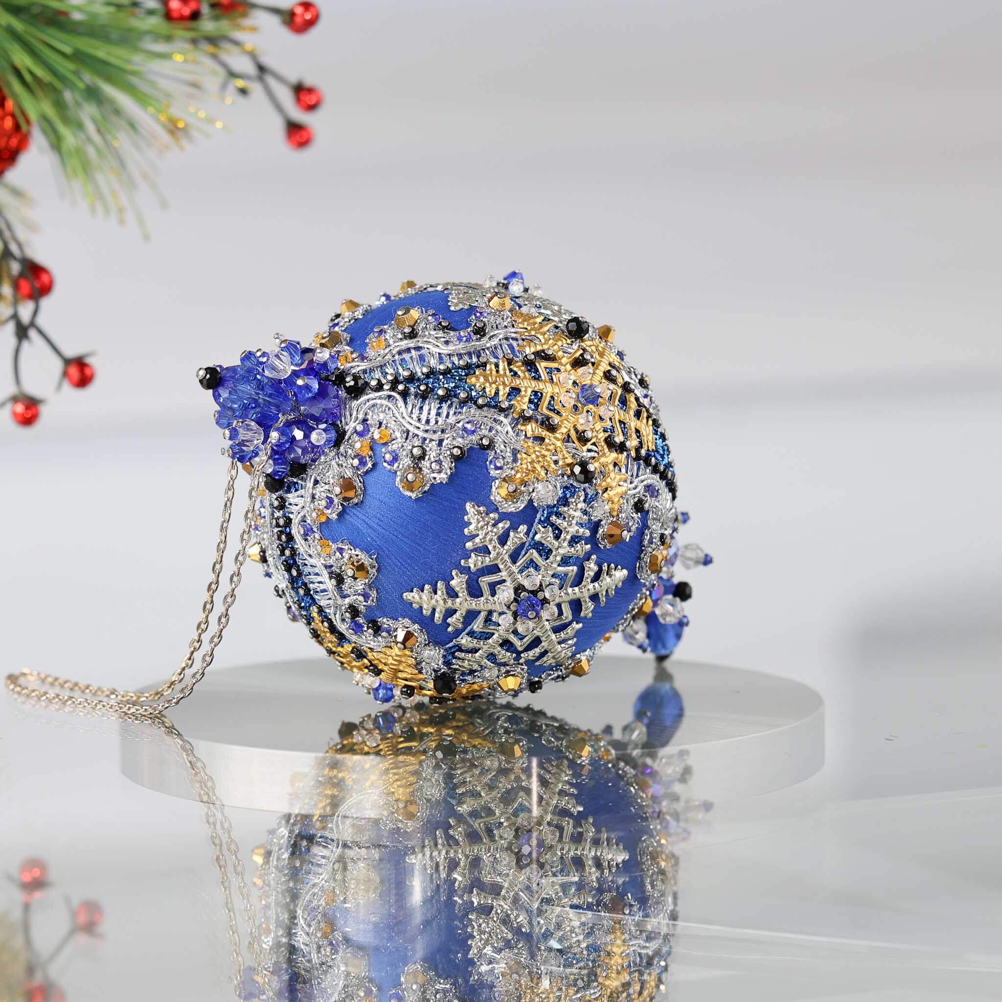 Decorative handmade blue and gold ornament with intricate designs on a white background on a reflective surface. (Blue)