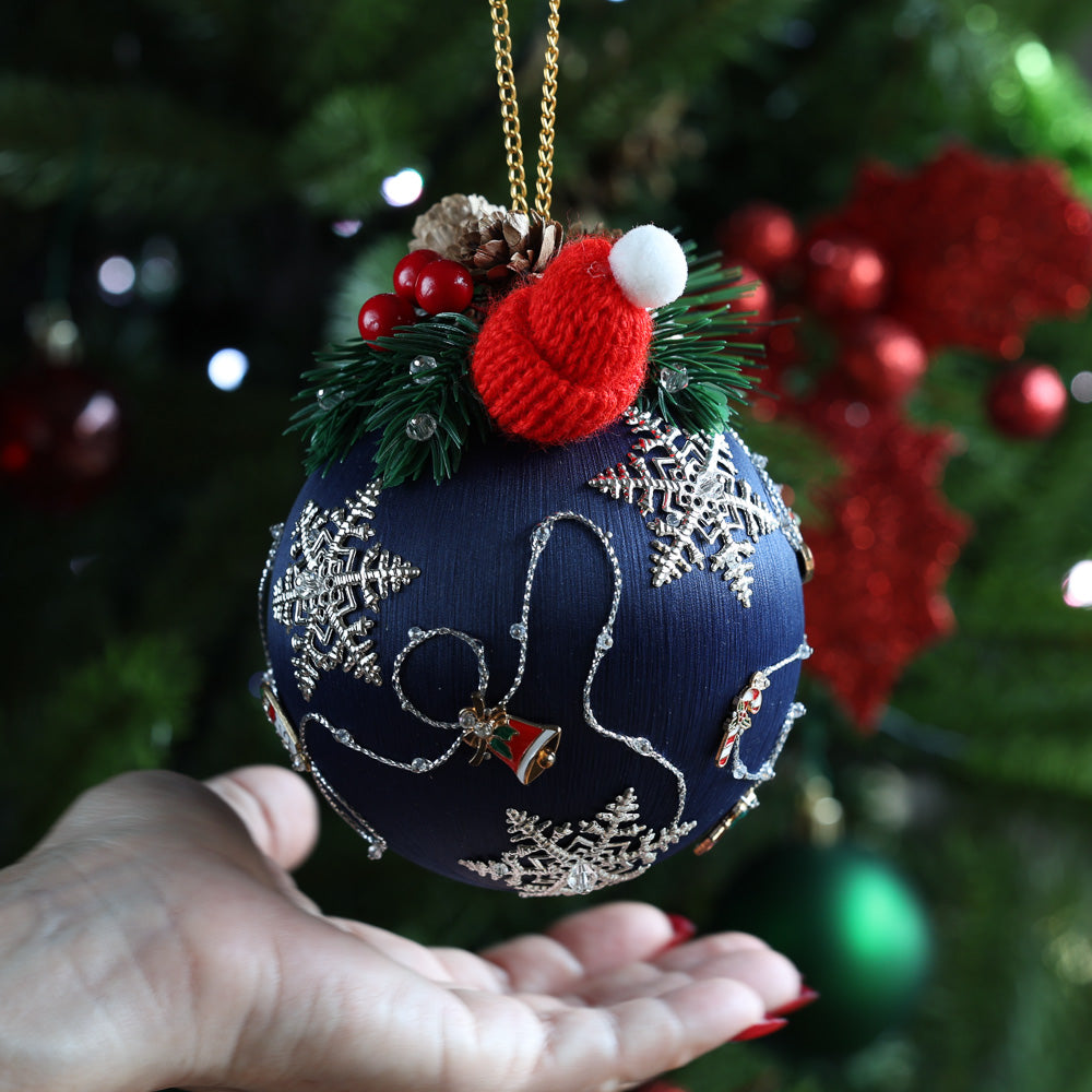 Handmade Push Pin Beaded Ornament with  pinecones and an adorable knit mini hat with a hand showcasing large 4” size in front of a christmas tree by Whim5seasons.