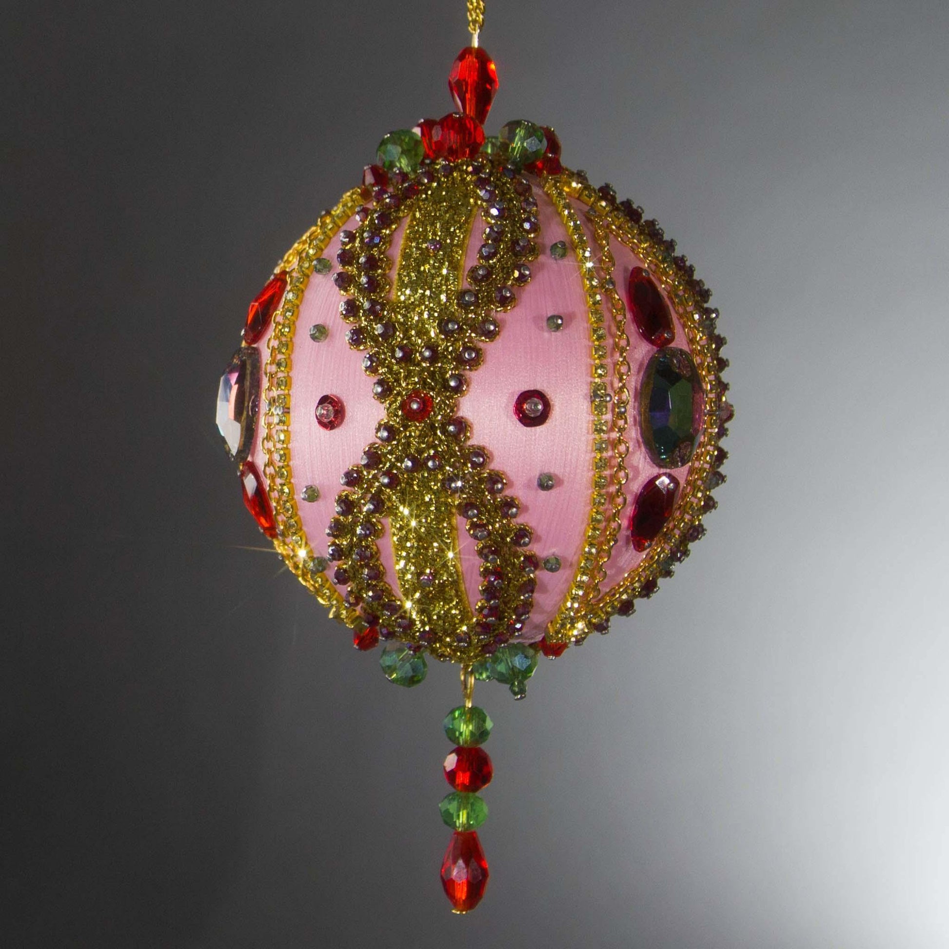 Handmade pink Christmas Beaded decoration with a bright glass tassel hanging on a chain loop on a light gray background by Whim5seasons.