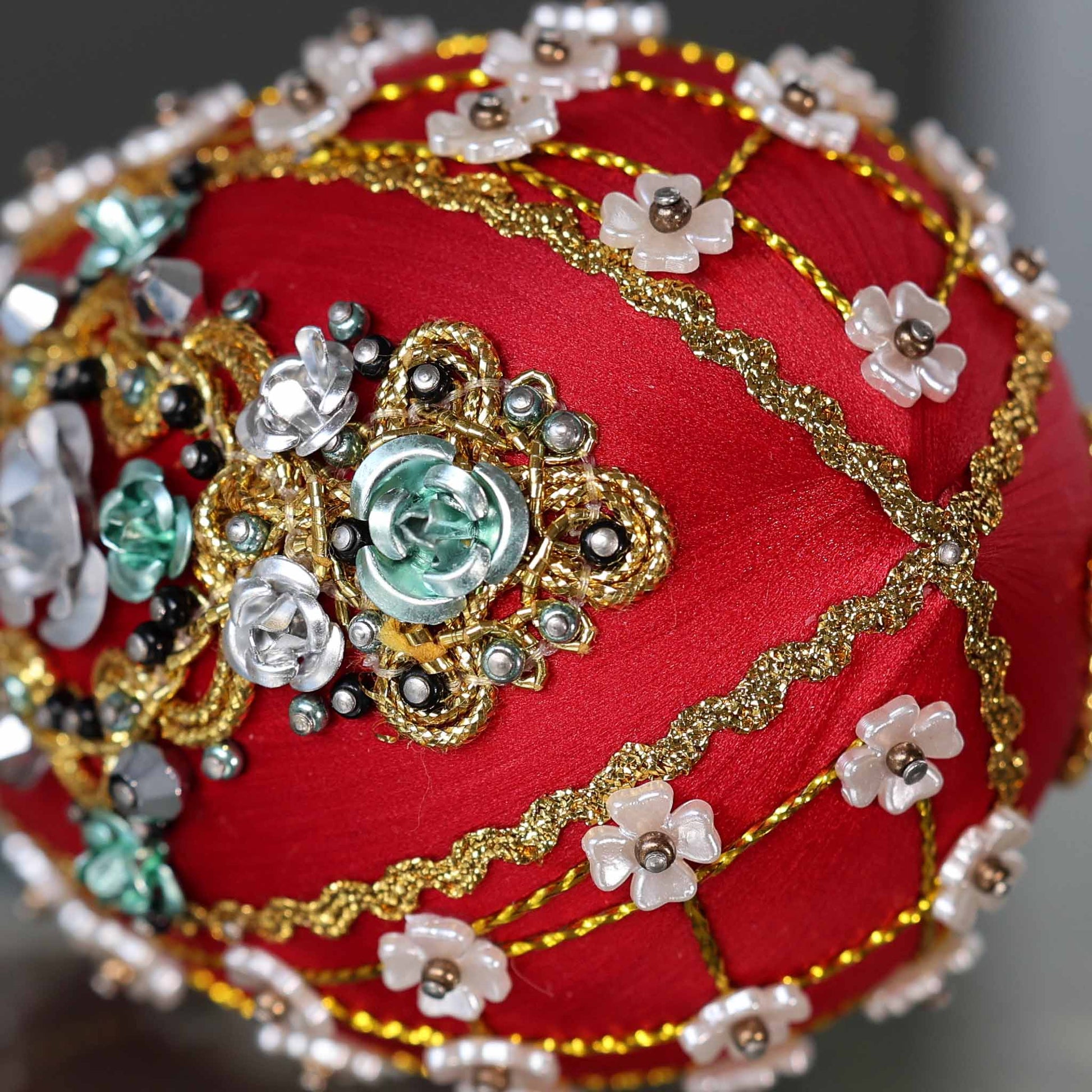 Close up of a handmade Easter Egg Push Pin Ornament embellished with crystals, beads, and metallic trim on a dark gray background by Whim5seasons. (Dark Red)