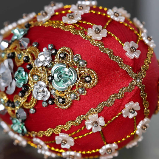 Close up of a handmade Easter Egg Push Pin Ornament embellished with crystals, beads, and metallic trim on a dark gray background by Whim5seasons. (Dark Red)