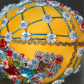 Load image into Gallery viewer, A close-up detail of a completed Easter egg push pin ornament featuring deep gold color with blue rose embellishments, pearlesque beads, and green acrylic leaf charms. (Dark Orange)
