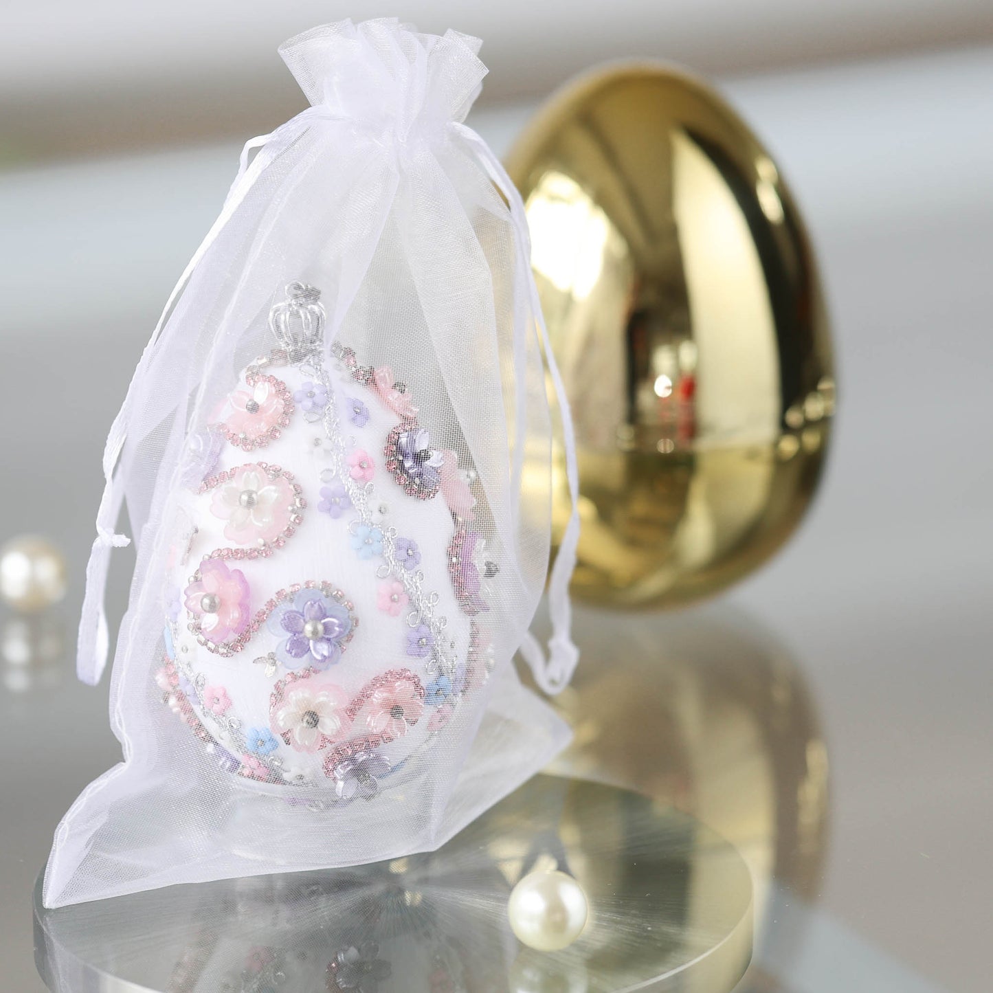 Handmade Easter egg push pin ornament in organza bag with a large gold egg container in the background featuring by Whim5seasons.