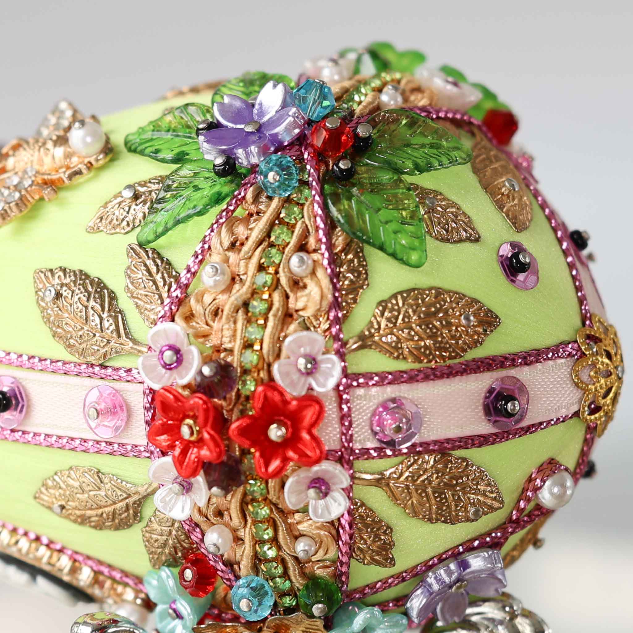 A close-up detail of a push pin Easter Egg showing small acrylic flowers pinned to a green satin foam core by Whim5seasons.