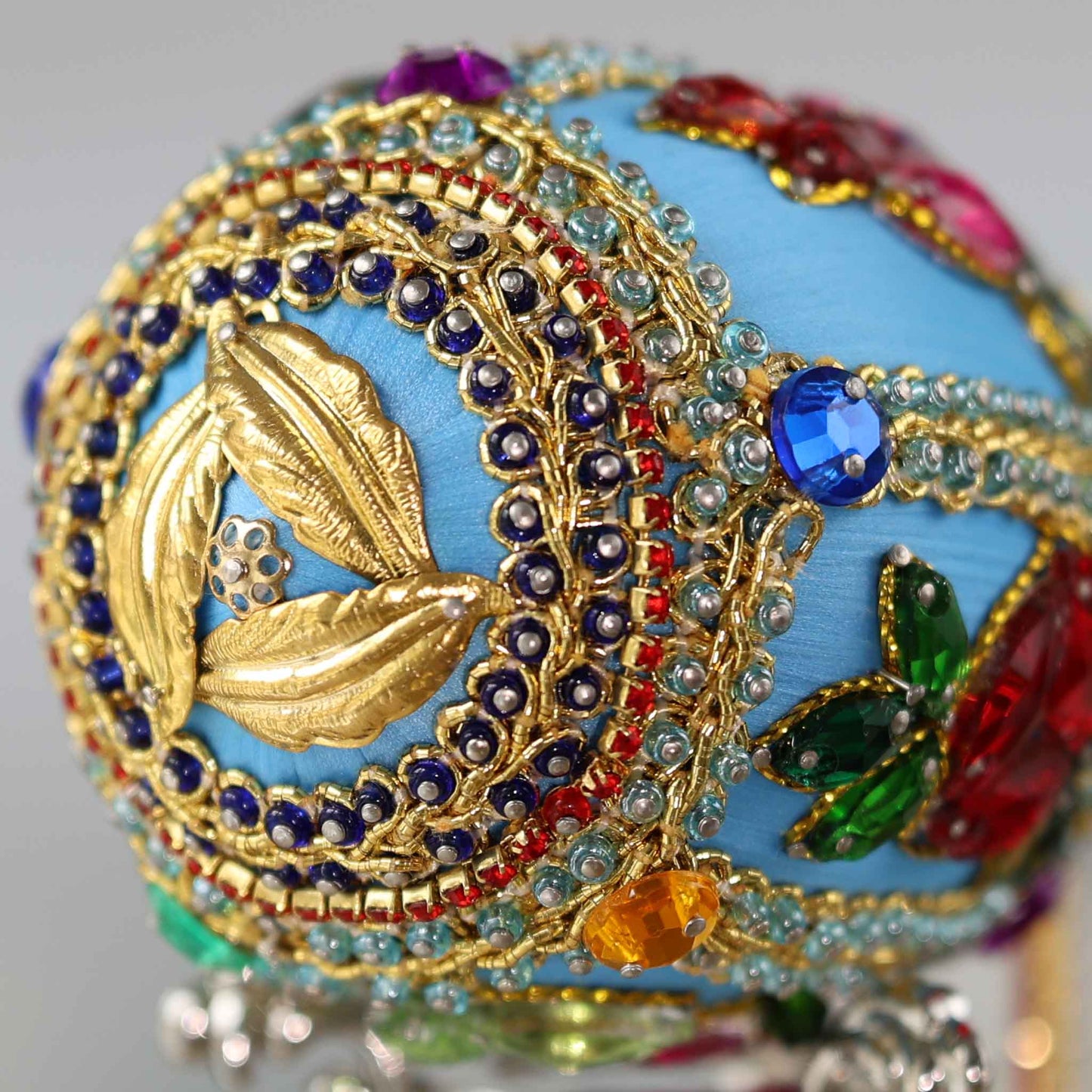 A close-up detail of a push pin Easter Egg ornament showing small glass rhinestones and seed beads pinned to a blue satin foam core by Whim5seasons.