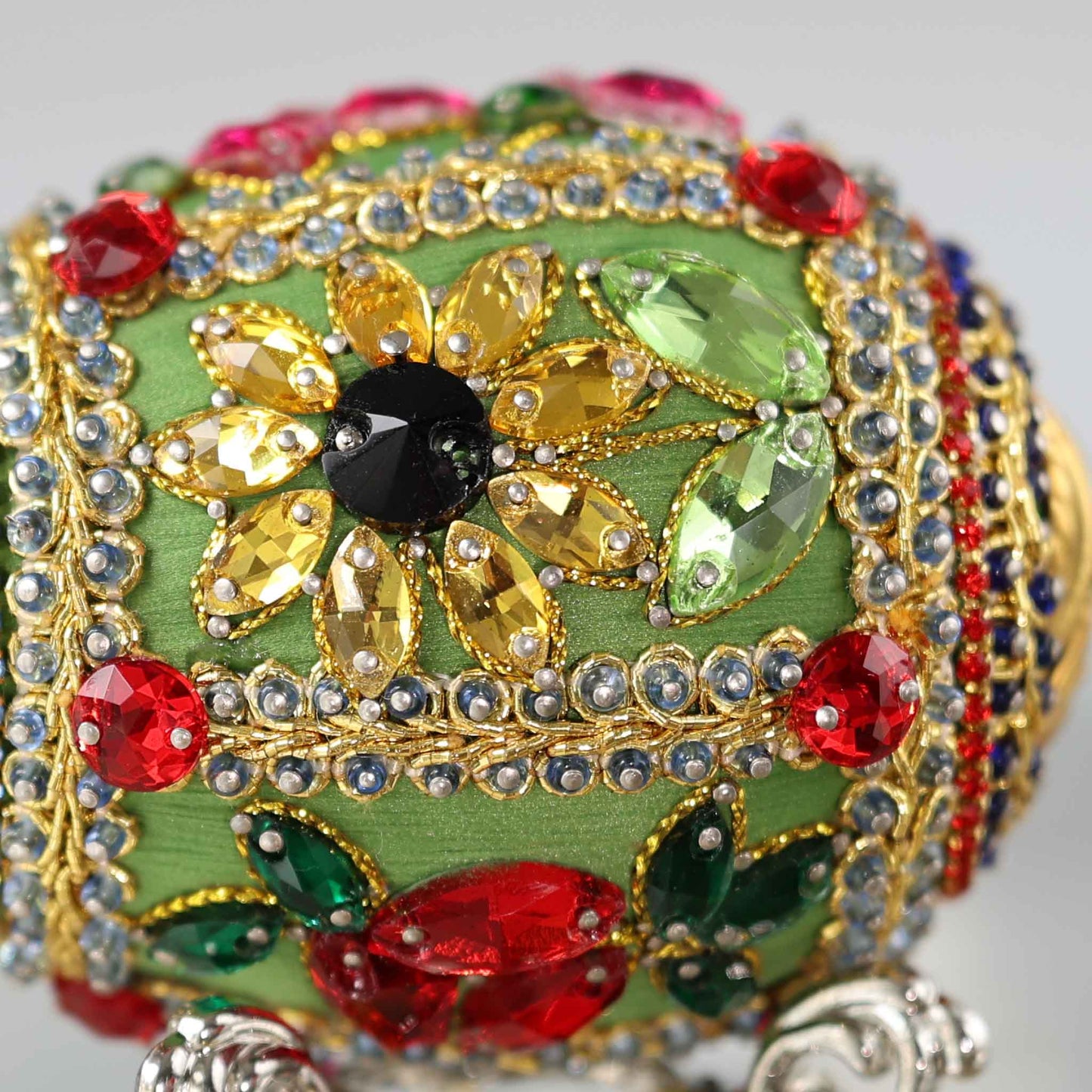 A close-up detail of a push pin Easter Egg showing glass rhinestone flowers pinned to a green satin foam core by Whim5seasons.