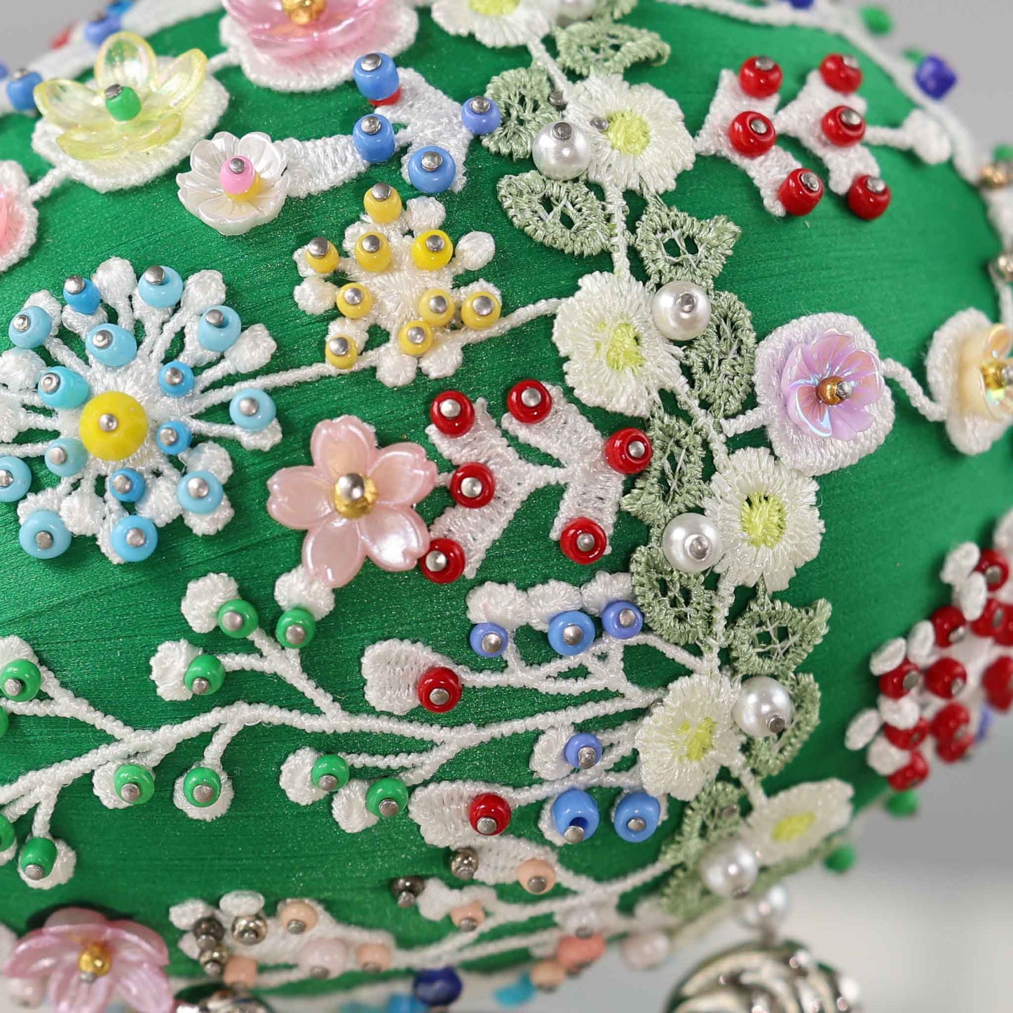 A close-up detail of a green Easter egg push pin ornament showing small beads and pearls pinned with dressmaker pins to the satin core by Whim5seasons.