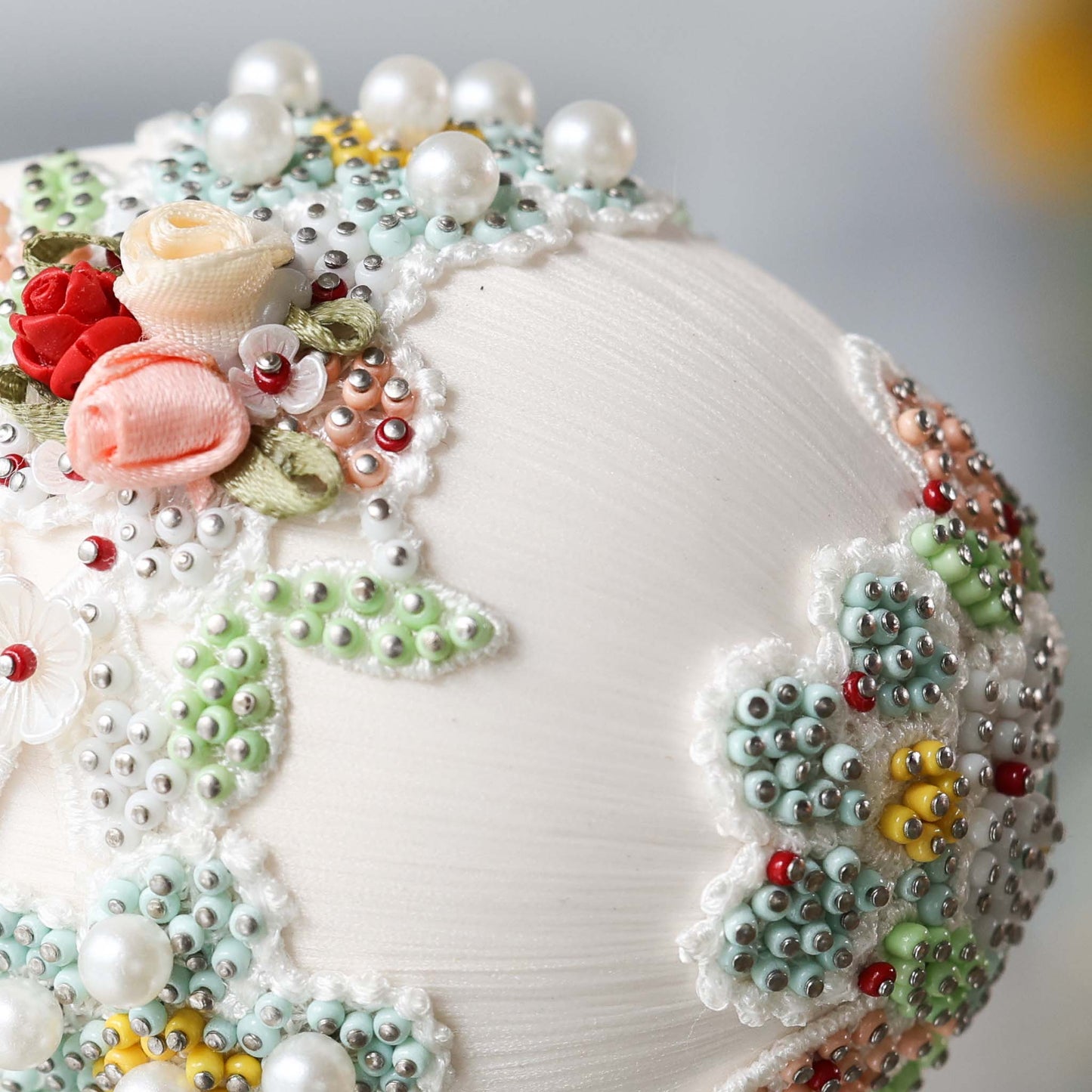 Close-up detail of an almond-colored handmade large satin Easter egg push pin ornament with floral lace and hundreds of beads attached with dressmaker pins by Whim5seasons.