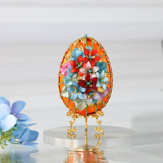 A handmade large Easter egg push pin ornament in gold and orange made with dressmaker pins, rhinestones, and beads. The DIY ornament is displayed on a gold stand.