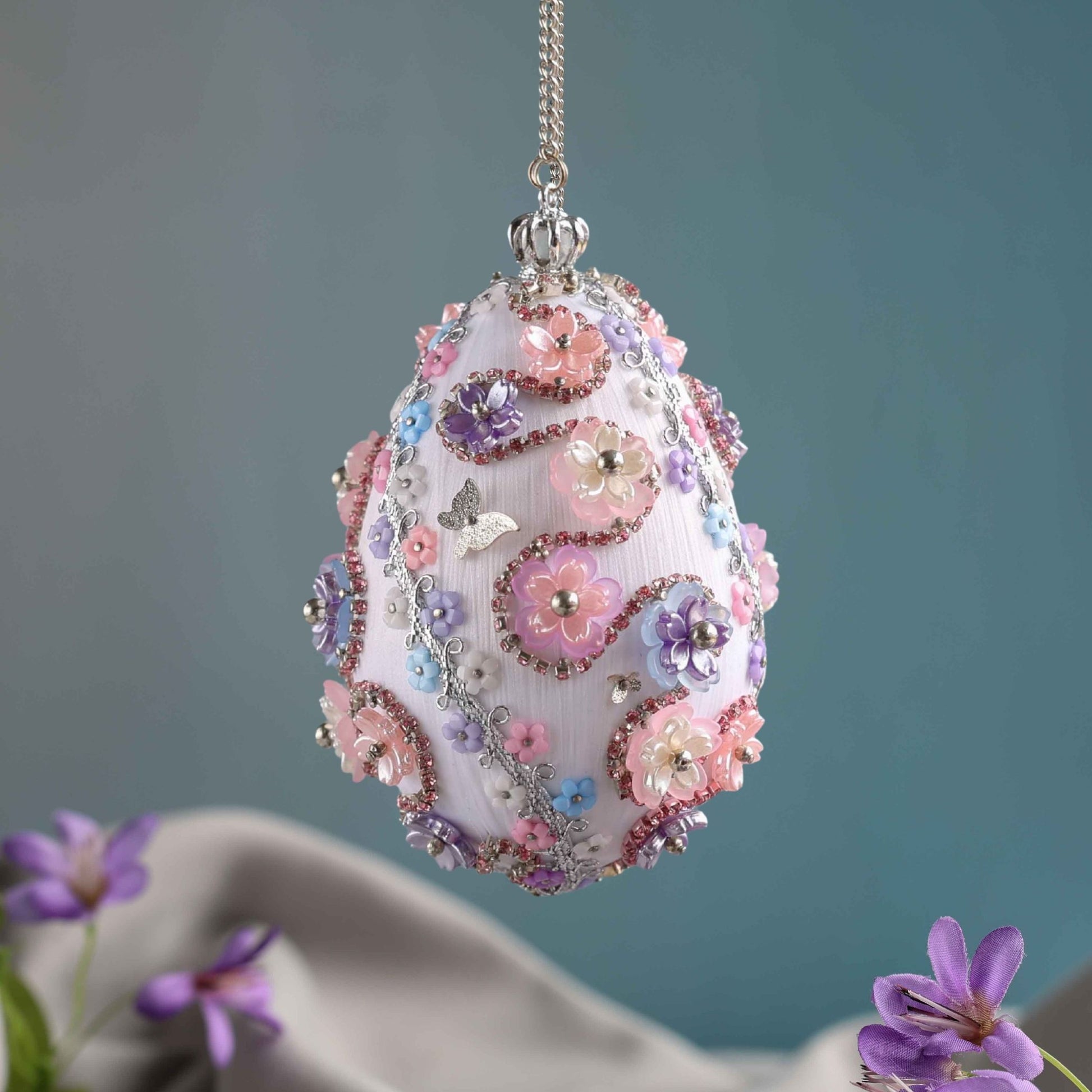 Beaded Push Pin Easter Egg Ornament hanging on a silver chain embellished with pink flowers on a blue background by Whim5seasons. (Silver)