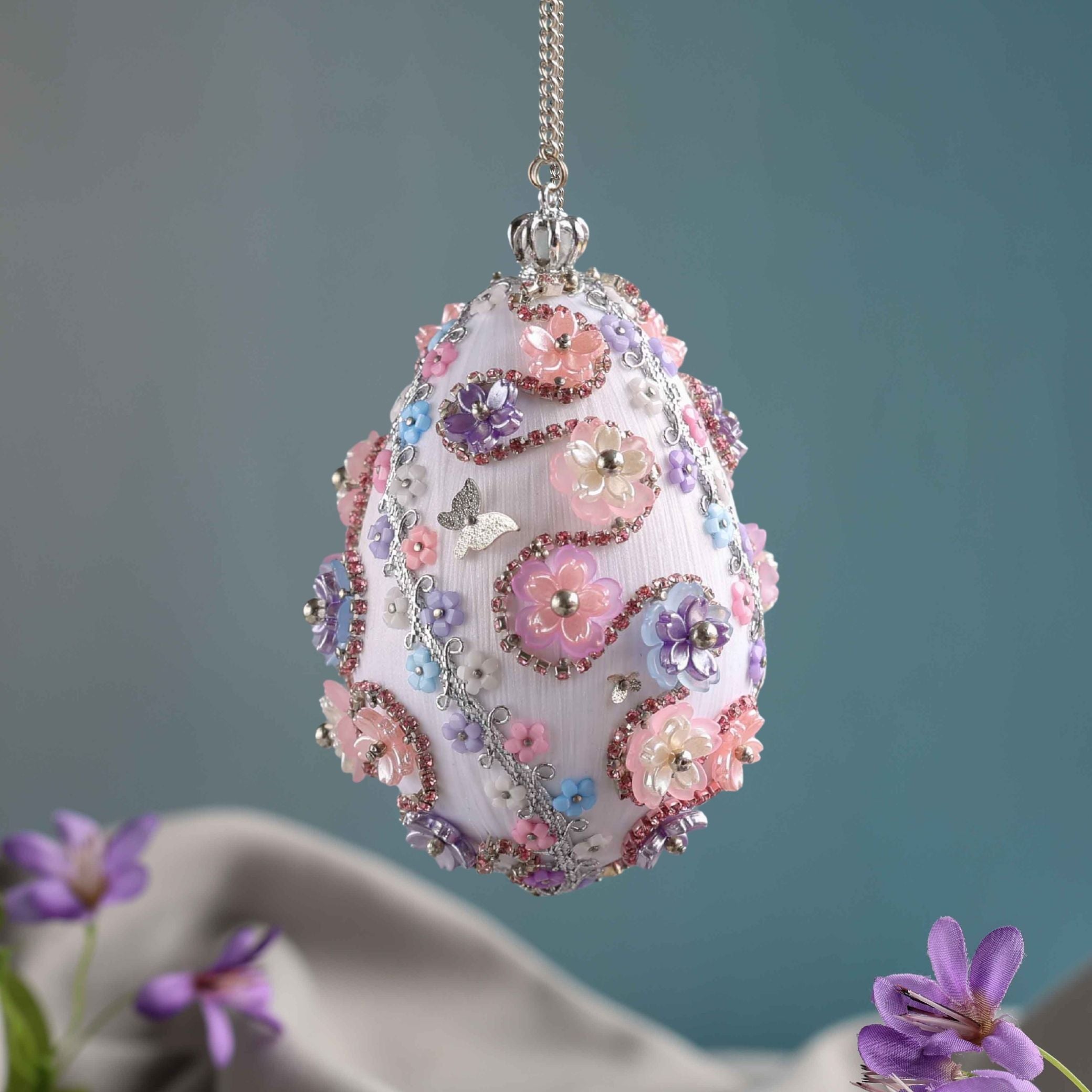 Beaded Push Pin Easter Egg Ornament hanging on a silver chain embellished with pink flowers on a blue background by Whim5seasons. (Silver)