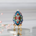 Load image into Gallery viewer, Luxurious handmade dark teal push pin Easter Egg ornament on a gold stand set against a light background featuring red roses, silver cording, and sparkly beads.  (Dark Slate Blue)
