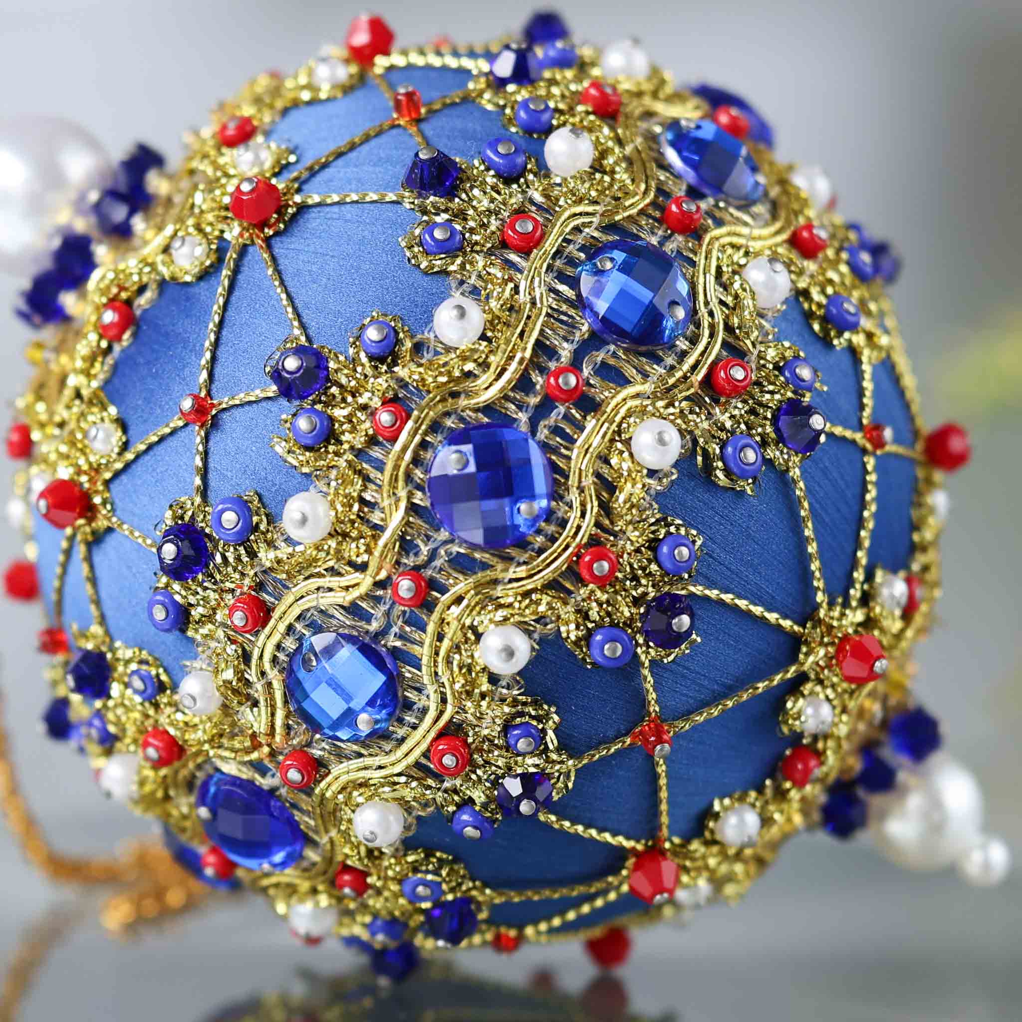 Close-up detail of a handmade push pin ornament - dark blue satin foam ball with indigo rhinestones, gold accents, seed beads, and pearls. (Dark Slate Blue)