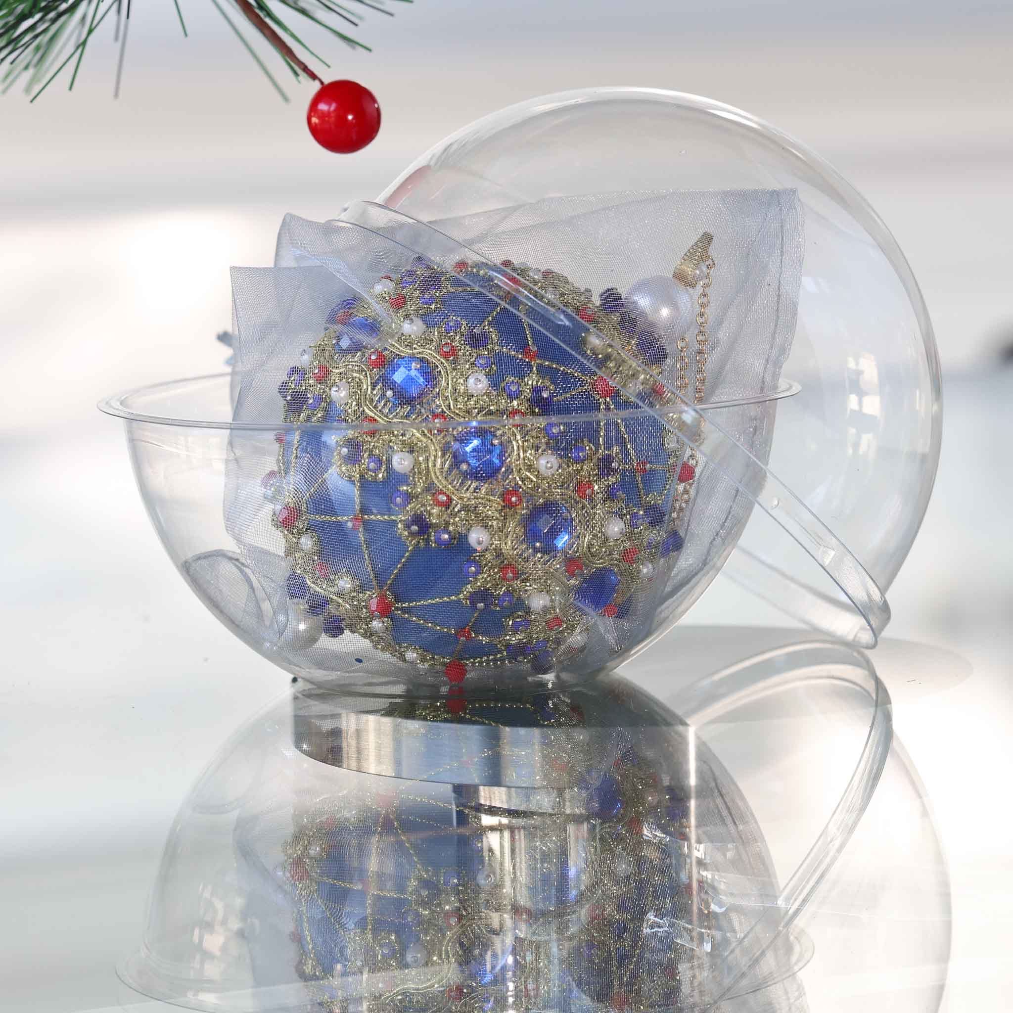 Bright blue festive handmade Christmas ornament with rhinestones, gold trim, sequins, in a container on a reflective surface set against a light gray background. (Dark Slate Blue)