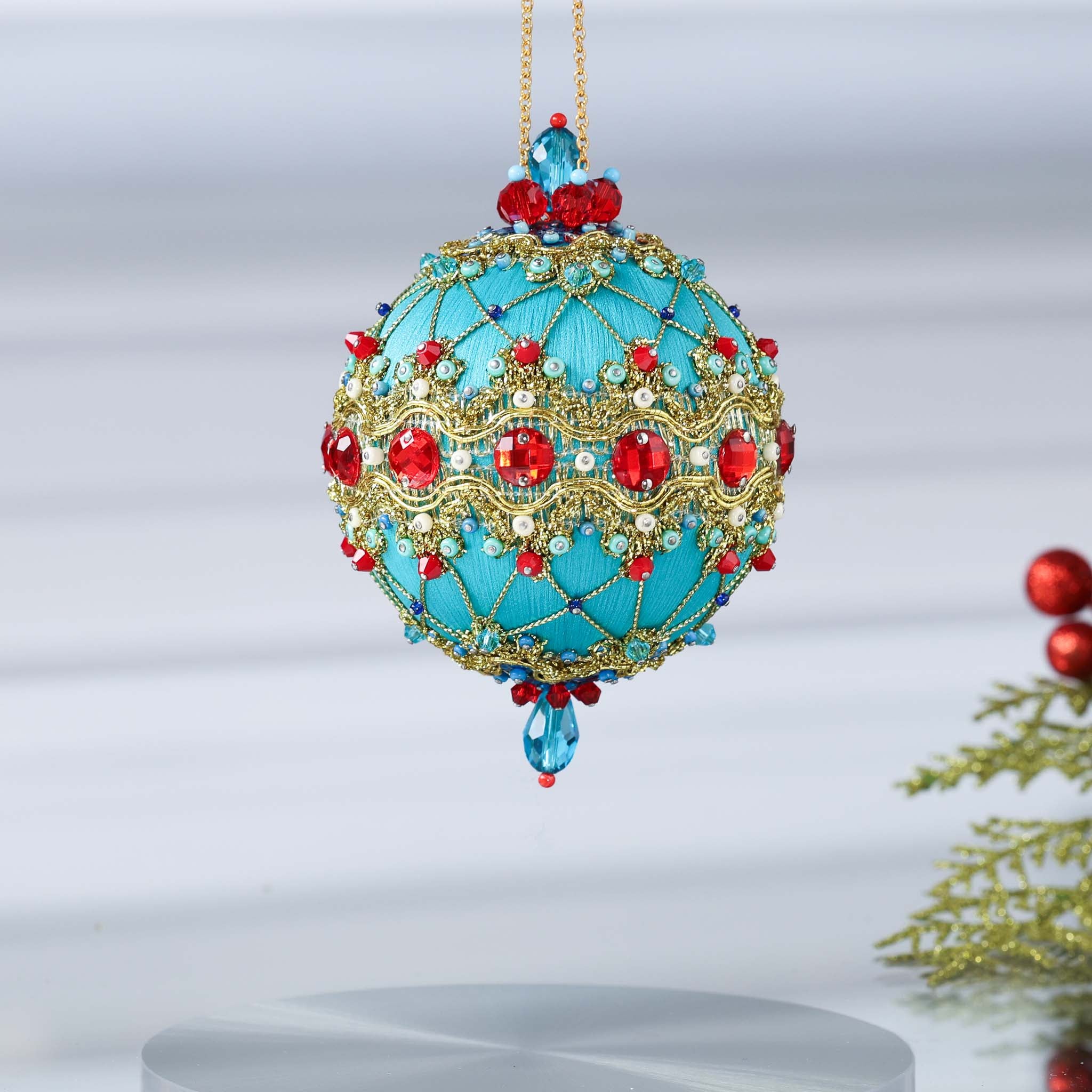 Hanging on a gold chain is a handmade push pin ornament - the color is light sea green, embellished with red rhinestones, red bicone beads, sequins, and metallic cord. (Light Sea Green)