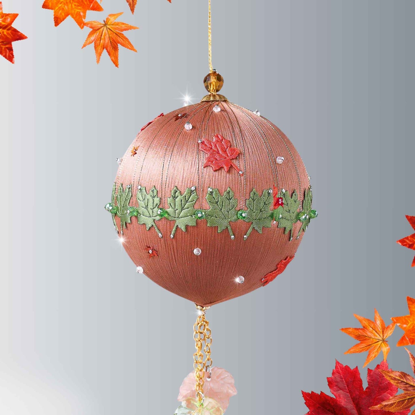 A Handmade Push Pin Ornament in brown color featuring a green maple ribbon trim pinned to a satin foam core with dressmaker pins, and some acrylic maple leaf charms, and clear seed beads by Whim5seasons.