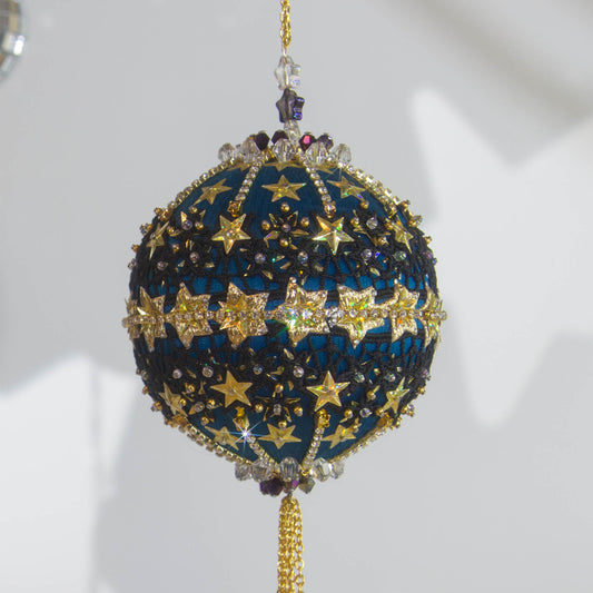 A close-up of a handmade New Year Star Ornament from Whim5seasons. It features sparkling rhinestones, and gold accents set on a rich fark blue satin ball. (Dark Slate Blue)