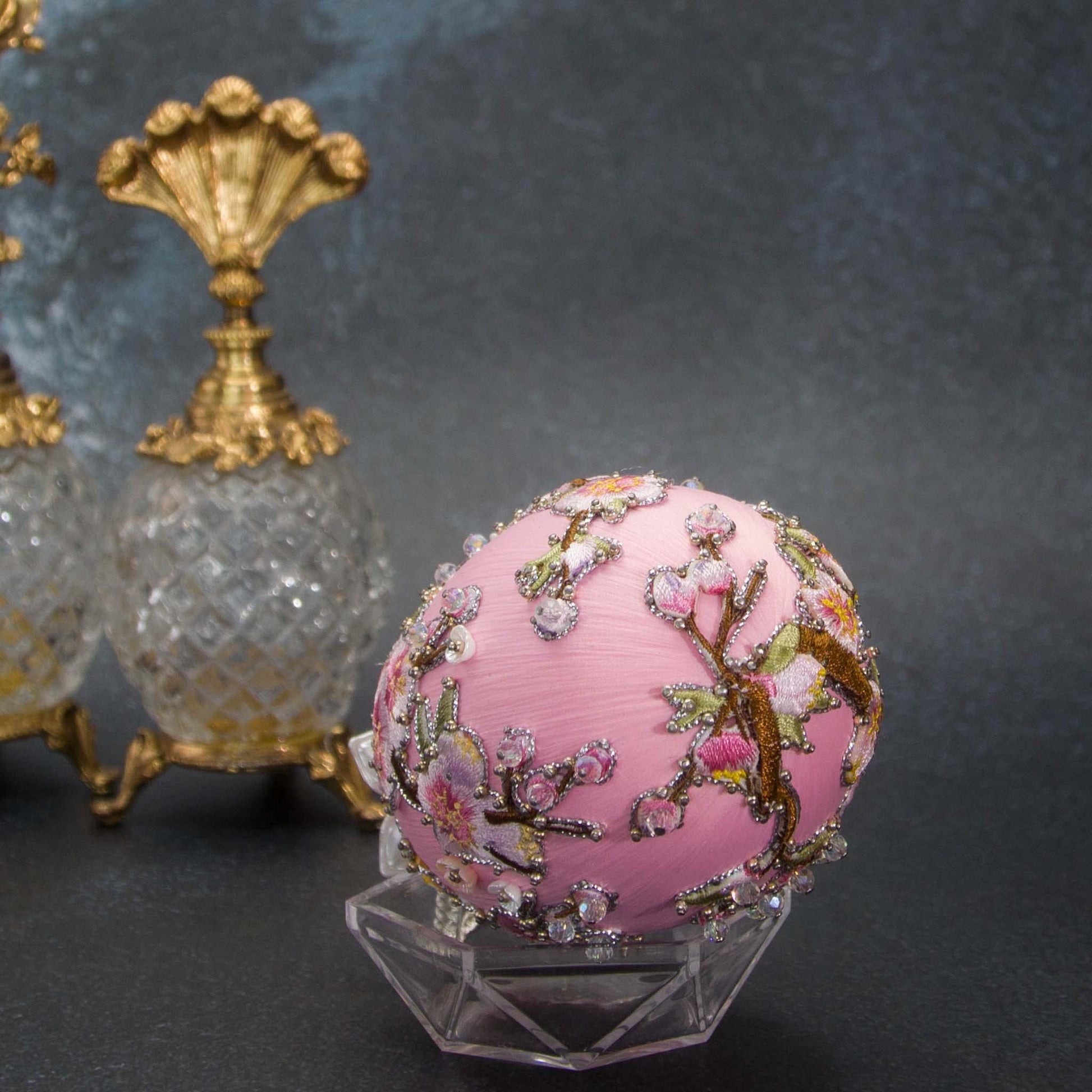 A bottom detail of Handmade Beaded Push Pin Easter Ornament  by Whim5seasons - white satin egg with pink plum bloom embroidery patches and silver cording. Faberge inspired.(Light Pink)