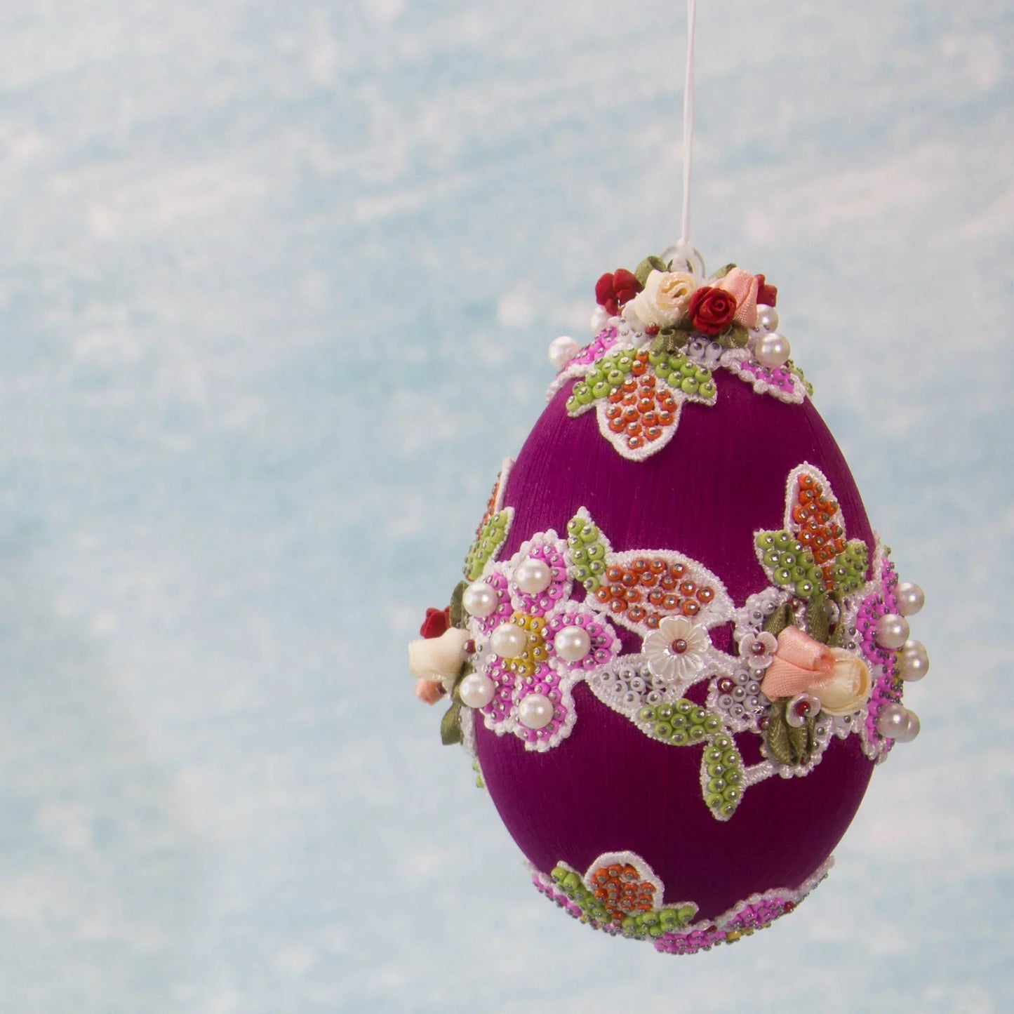 Vintage Doily in Hot Pink from Whim5seasons is a festive Easter Egg Ornament set against a background of a spring sky. (Purple) 