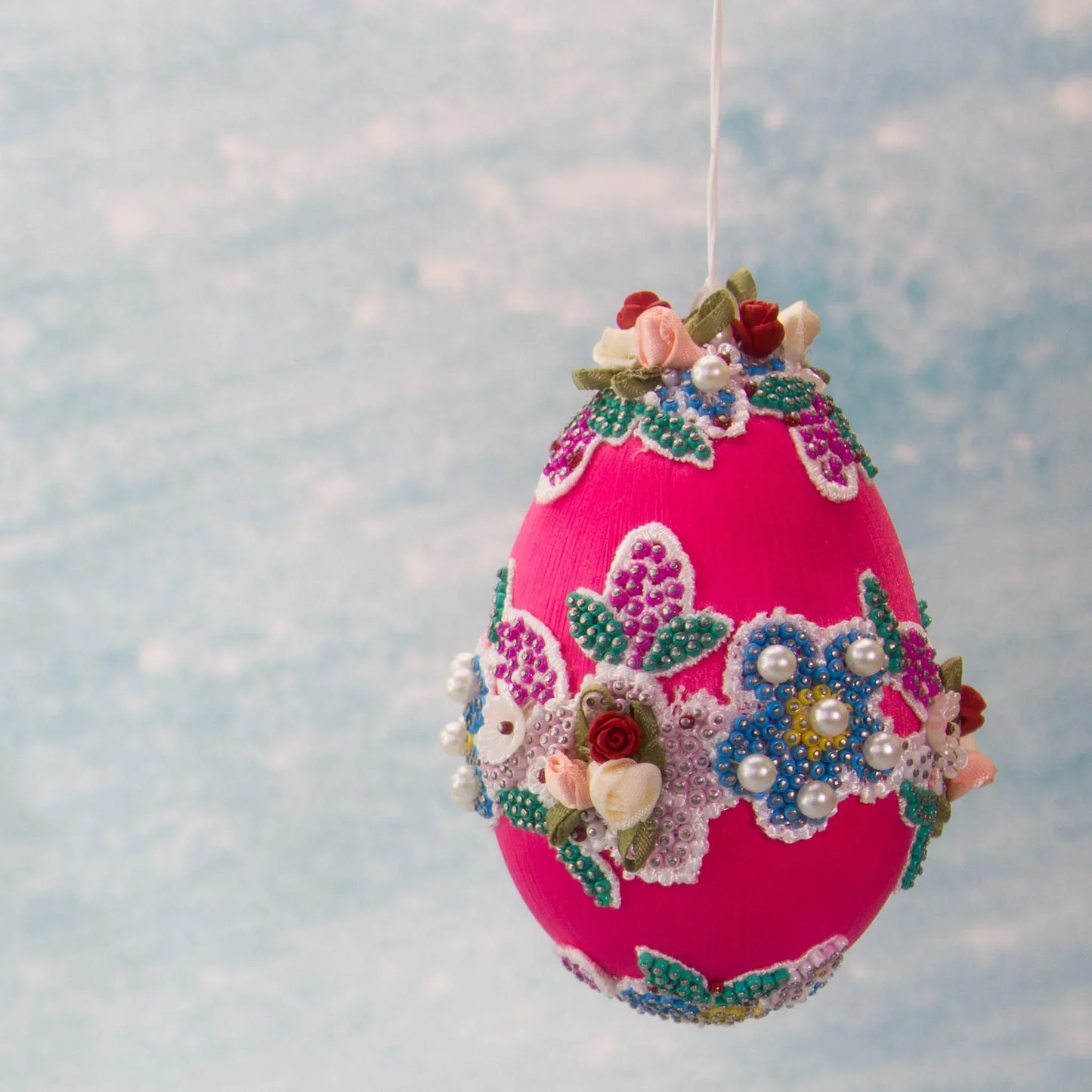 Vintage Doily in Hot Pink from Whim5seasons is a festive Easter Egg Ornament set against a background of a spring sky. (Deep Pink) 