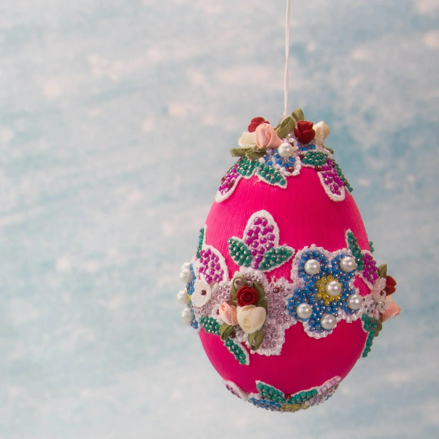 Vintage Doily in Hot Pink from Whim5seasons is a festive Easter Egg Ornament set against a background of a spring sky. (Deep Pink) 